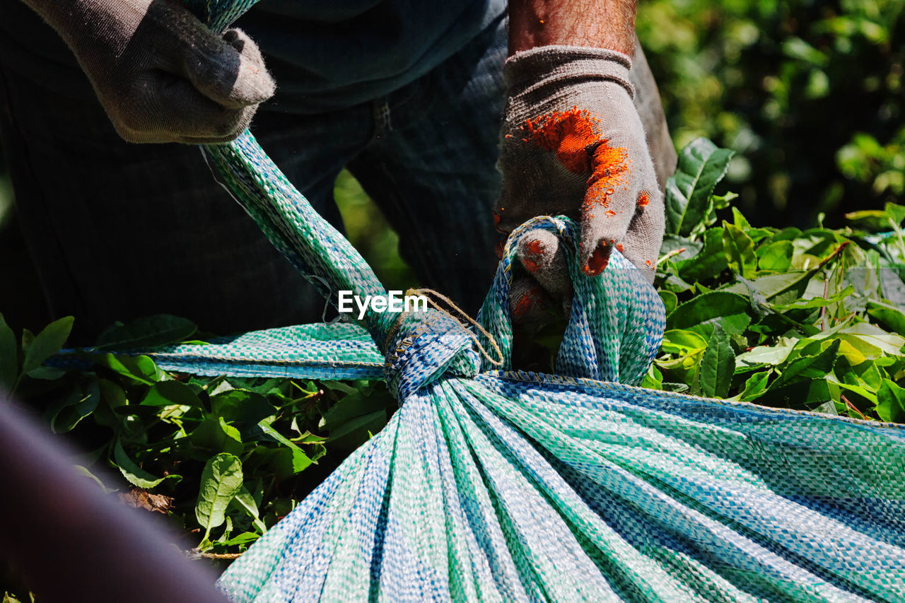 Midsection of worker holding sack during sunny day