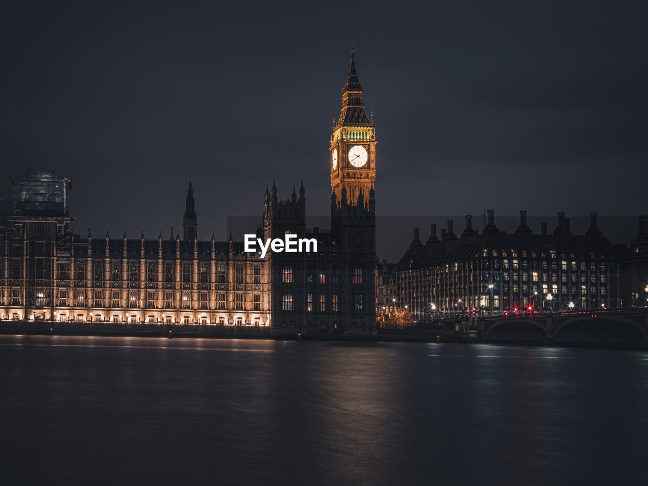 Big ben by river against sky in city at night