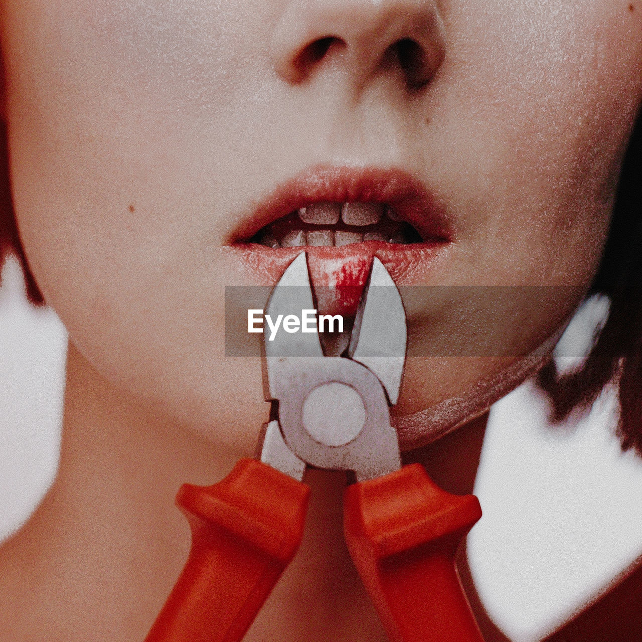 Midsection of woman cutting lips with pliers