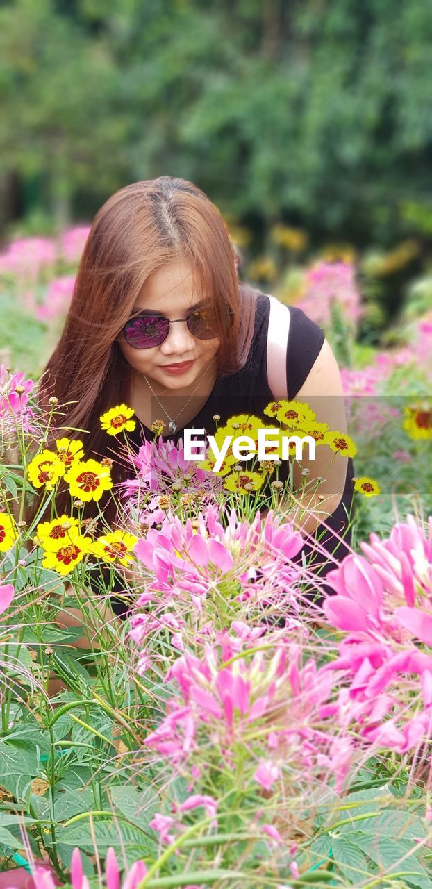 Woman looking at flowering plants on field