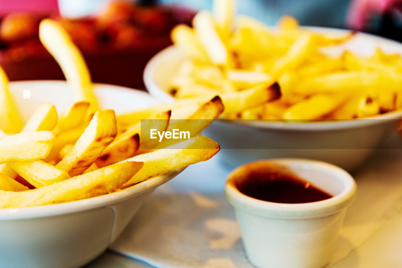 CLOSE-UP OF FRIES AND YELLOW BOWL ON PLATE
