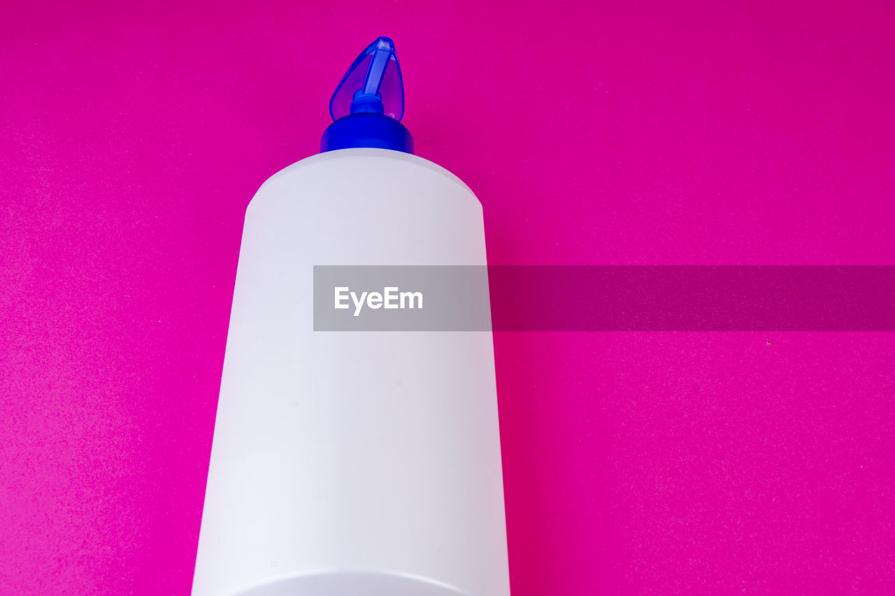 High angle view of soap dispenser against pink background