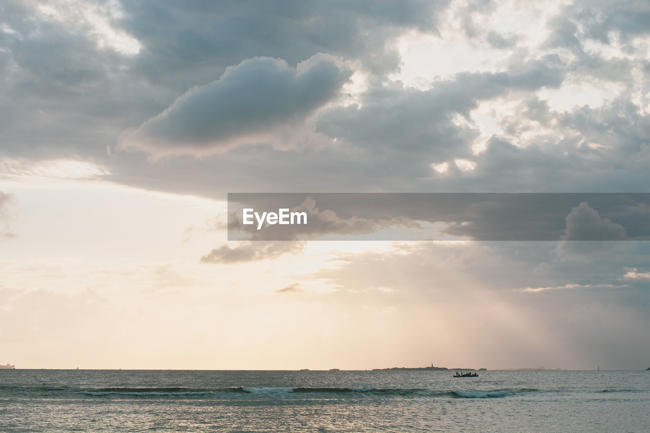 Scenic view of the ocean against cloudy sky during sunrise