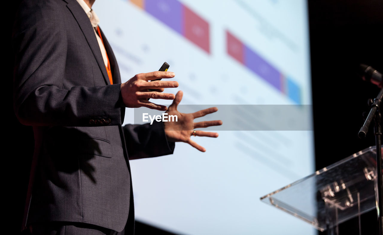 Midsection of man giving presentation at podium