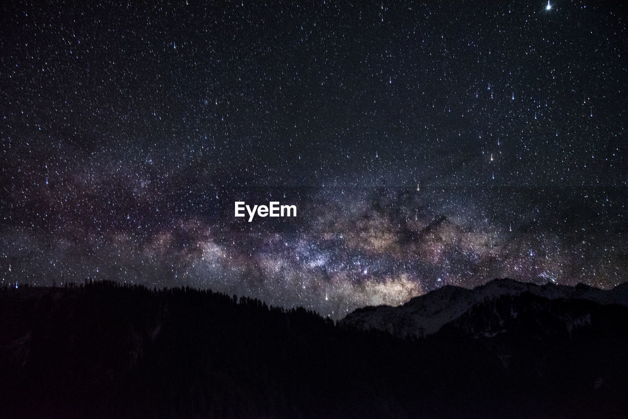 Scenic view of silhouette mountains against star field at night