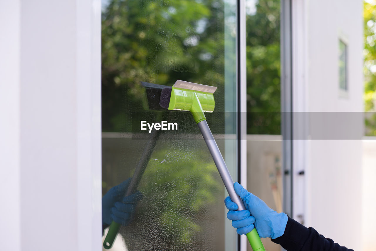 Cropped hand of person cleaning window glass