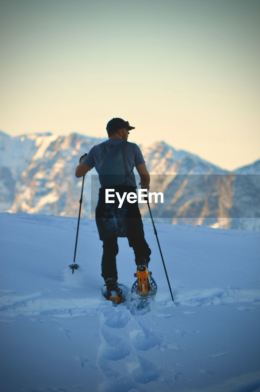 Rear view of man snowshoeing on mountain