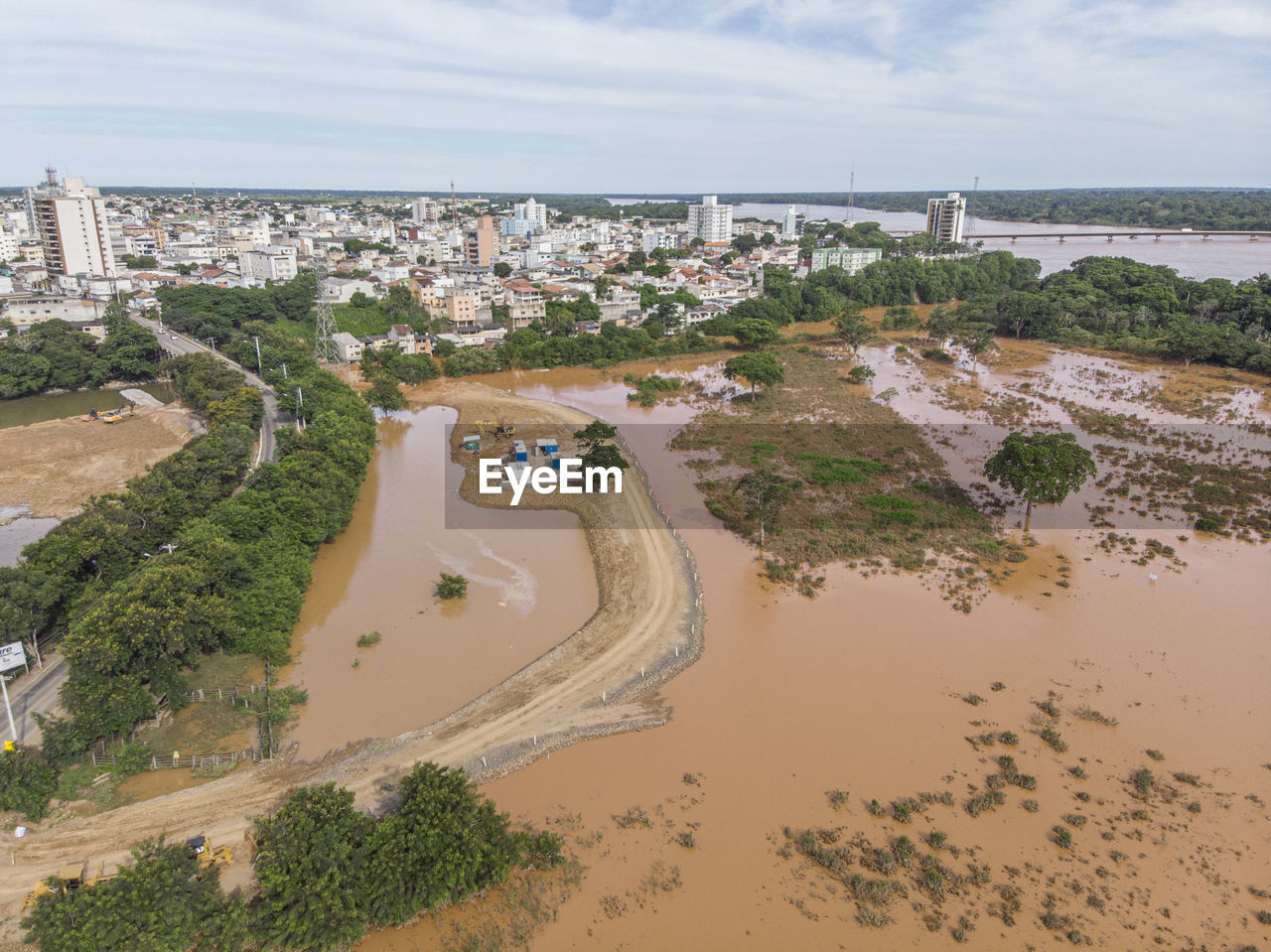 River flooding due to rain causes large mud next to a dam that prevents the rivers from meeting 