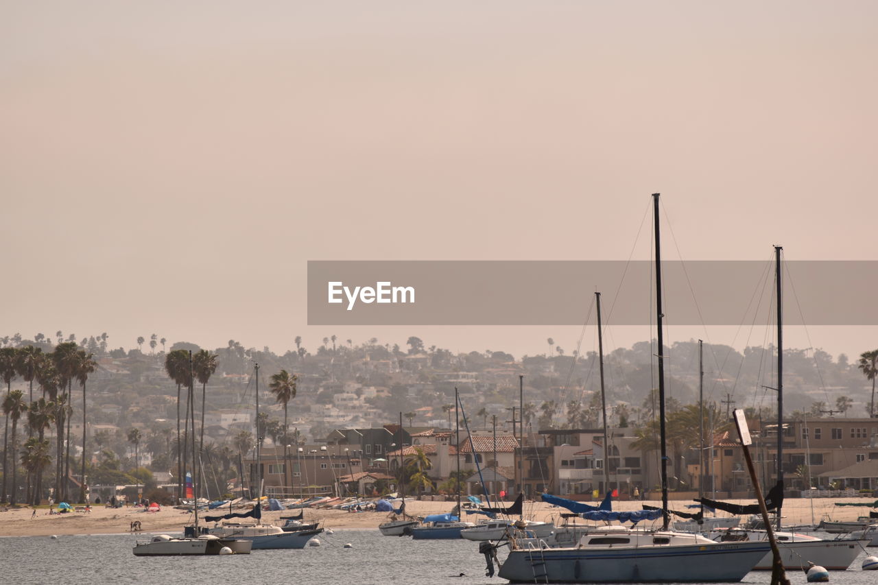 Sailboats moored in harbor at sunset