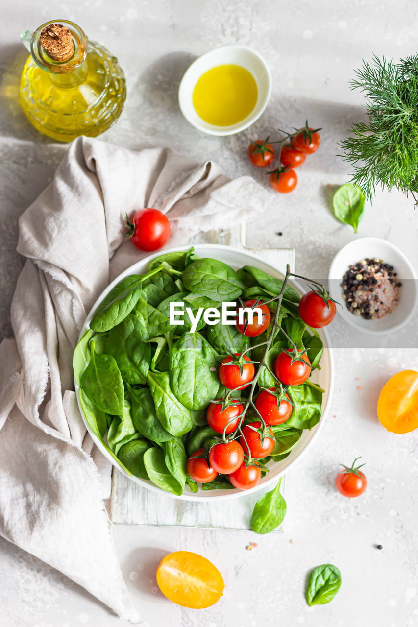 Baby spinach, red cherry and yellow tomatoes, dill and olive oil. fresh ingredients for salad. 