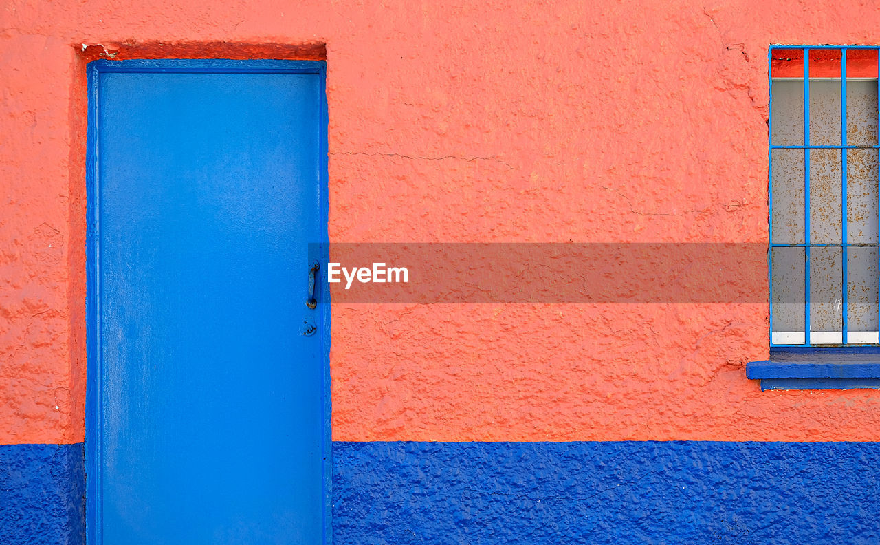 Close-up of blue door and red wall 