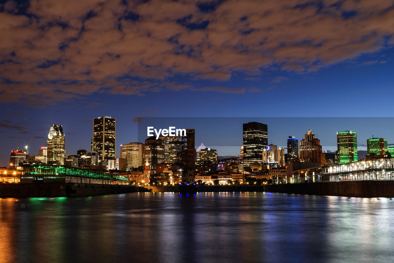 Colorful light reflecting on river against cityscape