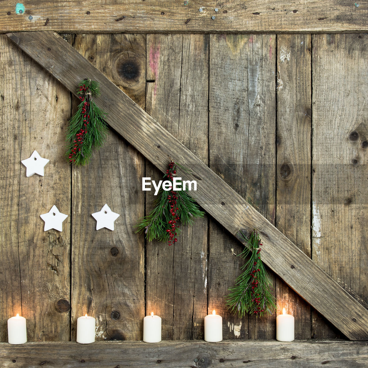 Close-up of candles burning on wooden wall during christmas