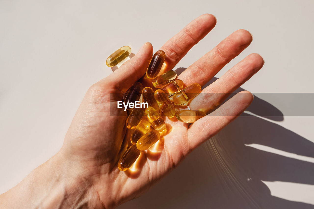 Woman's hand close-up holding a lot of gel pills, vitamin d or omega 3 oil. dietary supplement. 