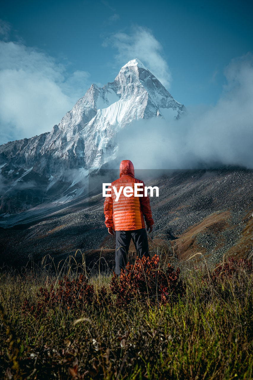 Rear view of person on snowcapped mountain against sky