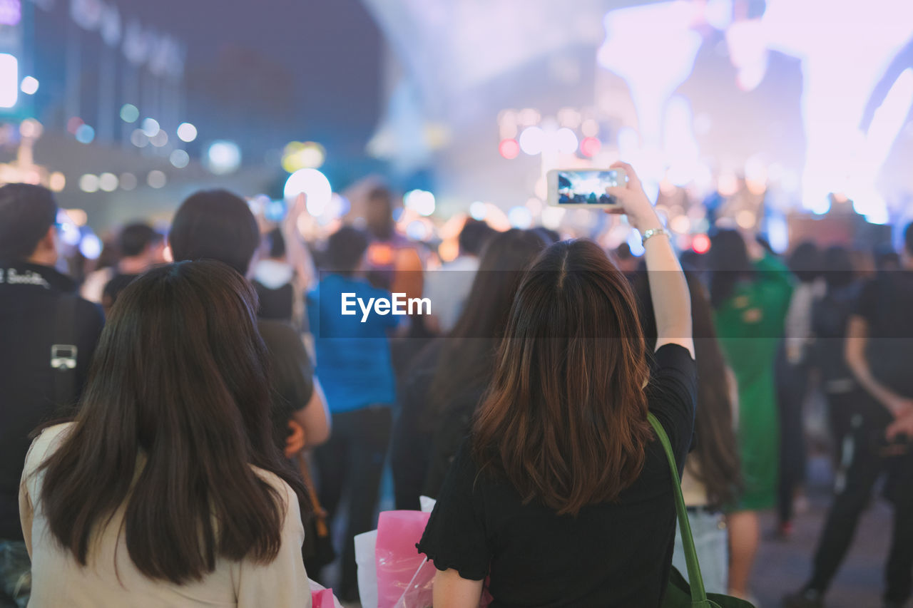 Nightlife and activity of people in new normal with asian woman take photo in outdoor concert 