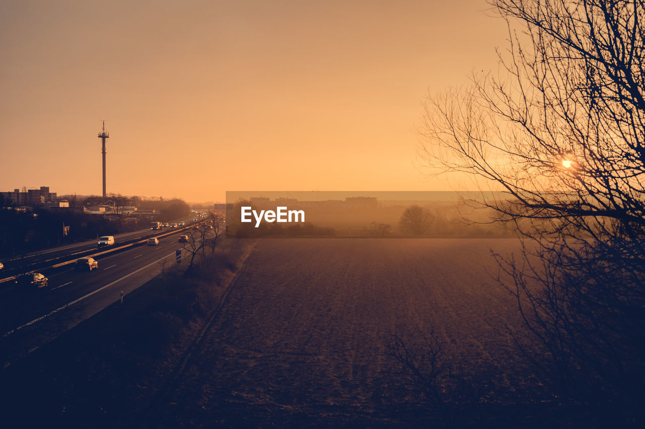 High angle view of field by highway against clear sky during sunrise