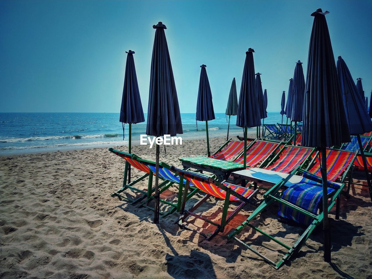 LOUNGE CHAIRS ON BEACH AGAINST SKY