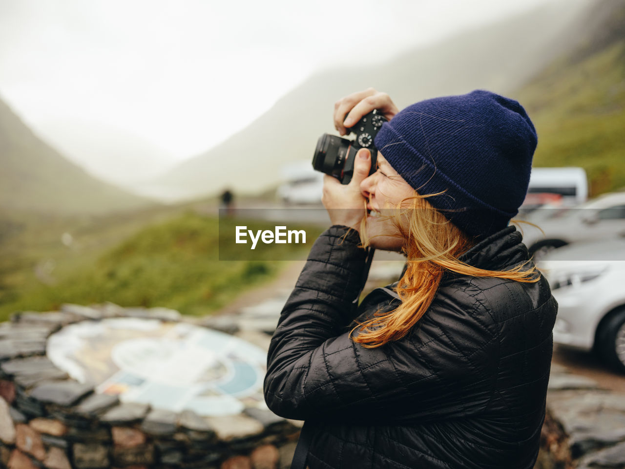 Woman photographing three sisters of glencoe, on a wet day