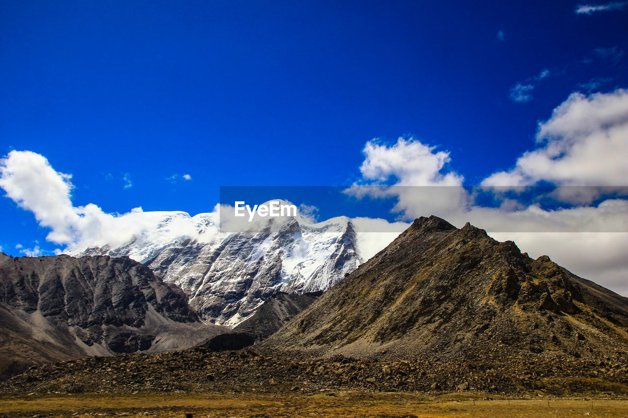 Scenic view of snowcapped mountains against blue sky