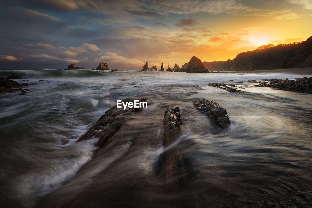 Scenic view of sea against cloudy sky during sunset