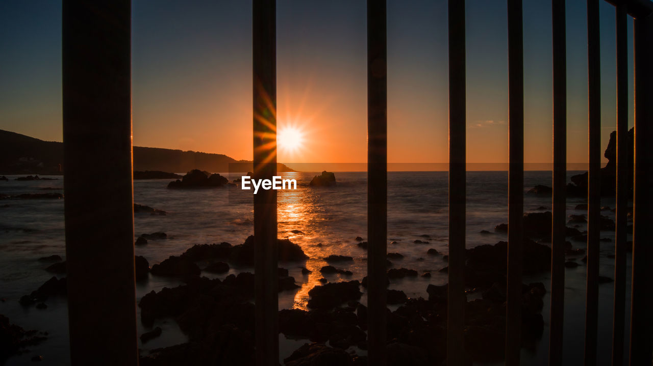 Scenic view of sea against bright sun during sunset