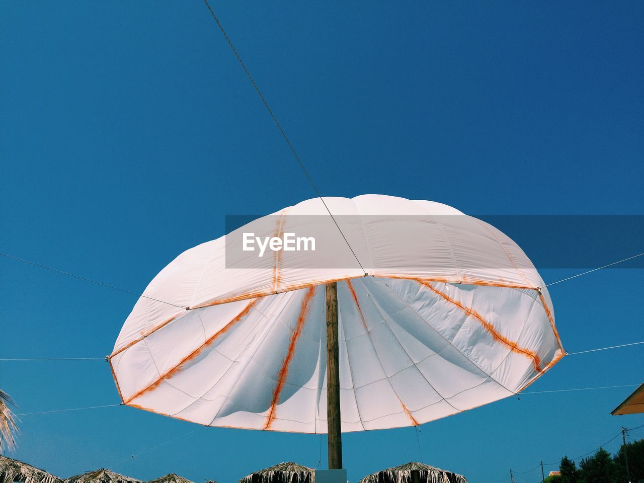 Low angle view of white parasol against clear blue sky