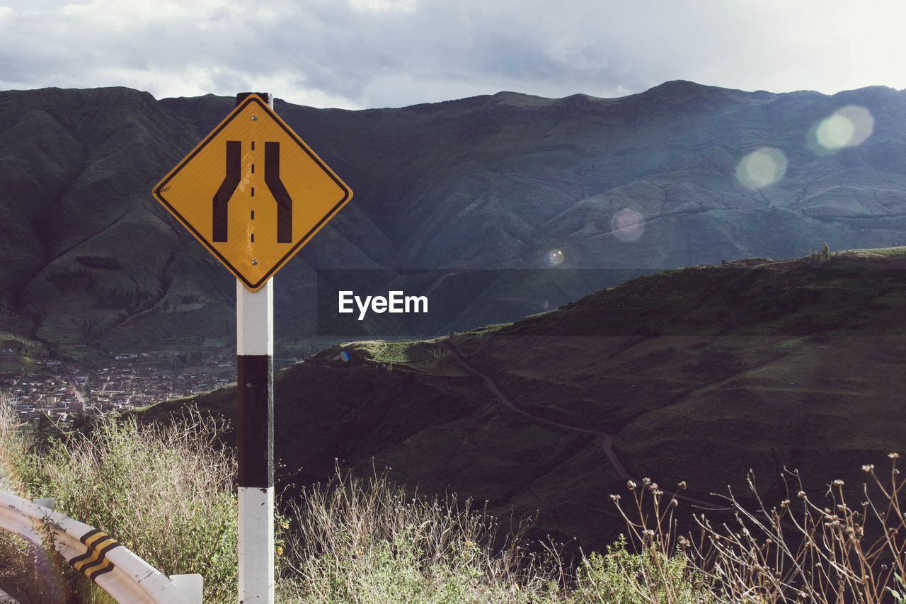 Road sign by mountains against sky