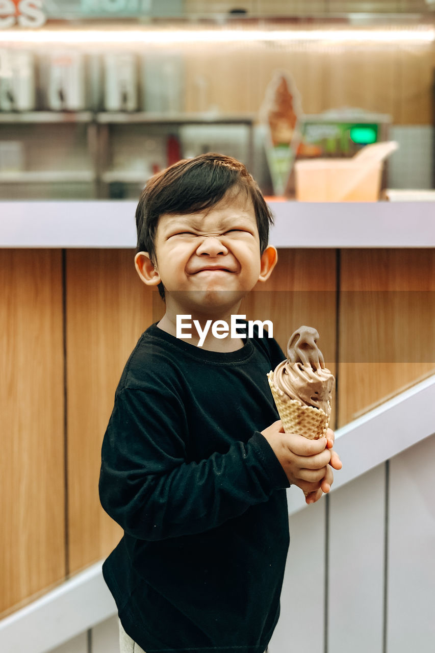 A boy is holding an ice cream with a happy smile