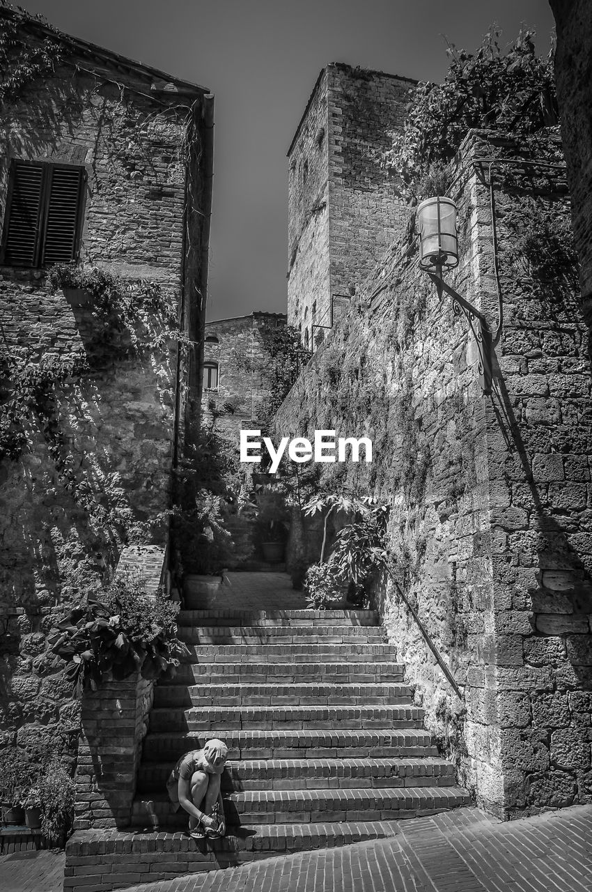 PEOPLE SITTING ON STAIRCASE BY BUILDING