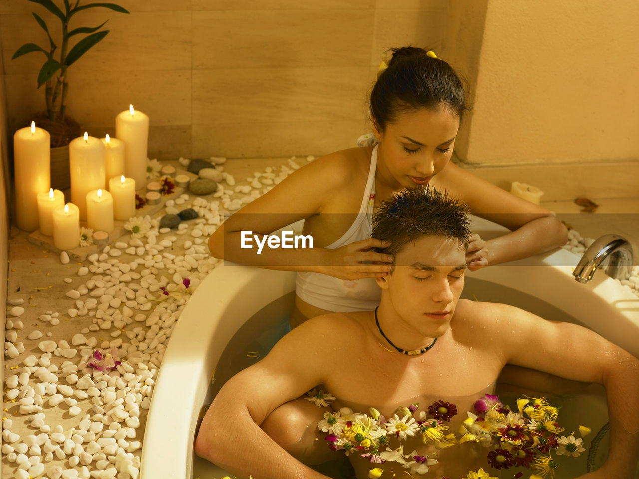 Girlfriend giving head massage to boyfriend in bathtub