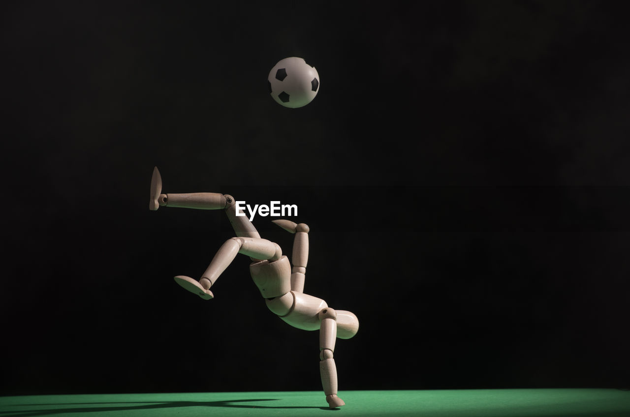 Close-up of figurine playing soccer against black background