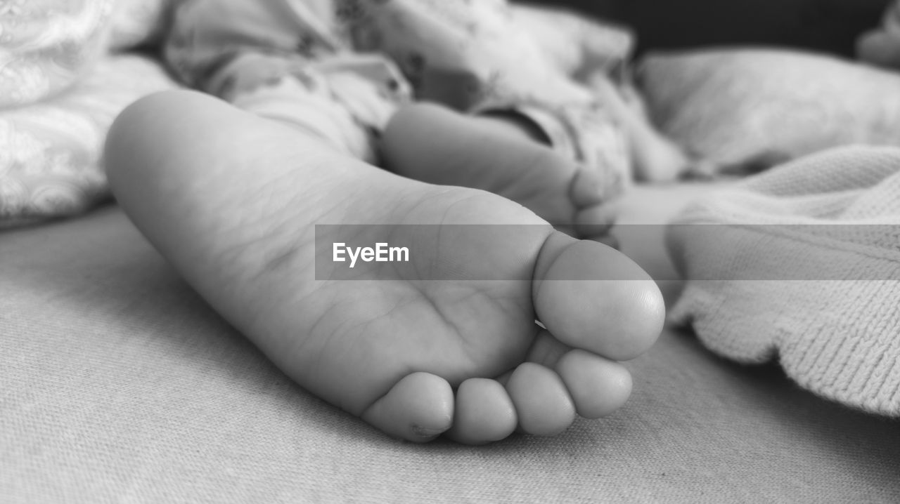 LOW SECTION OF BABY GIRL LYING ON BED