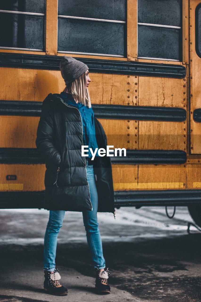 Young woman standing against bus