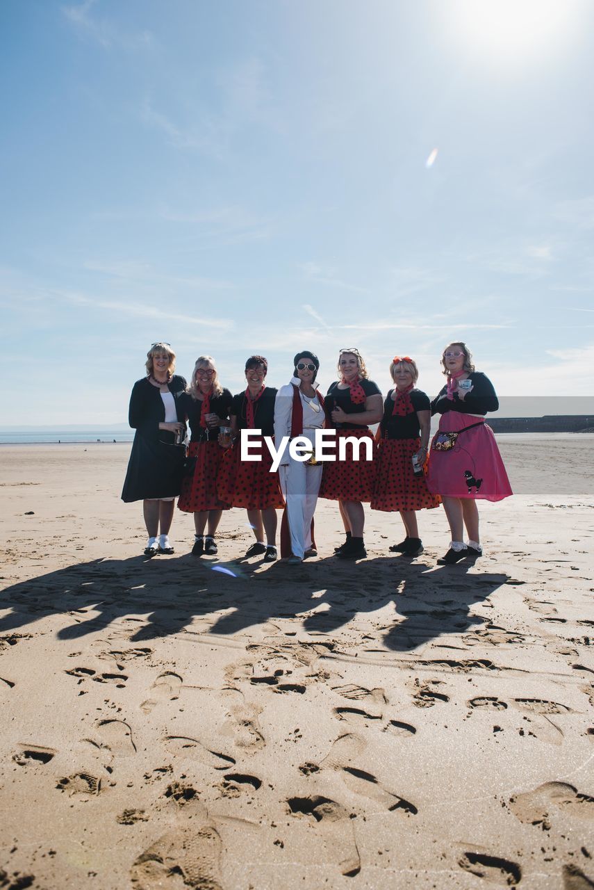 GROUP OF PEOPLE ON BEACH AGAINST SKY