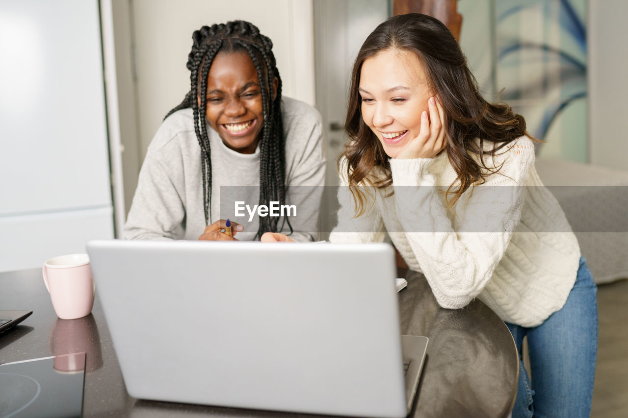 Smiling women looking at laptop at home