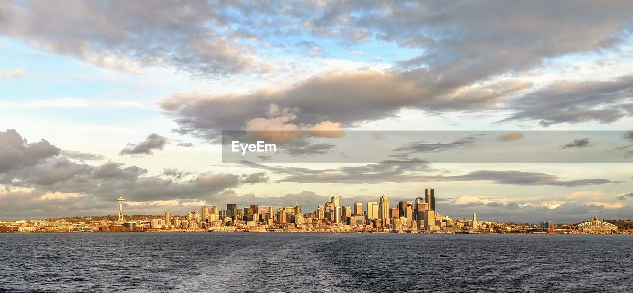 Panoramic view of sea and buildings against sky during sunset