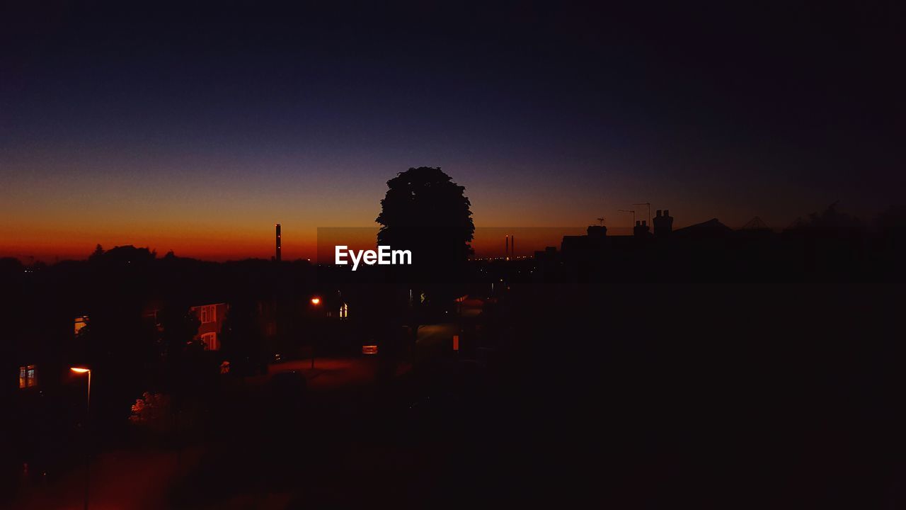 SILHOUETTE OF ILLUMINATED BUILDINGS AT SUNSET