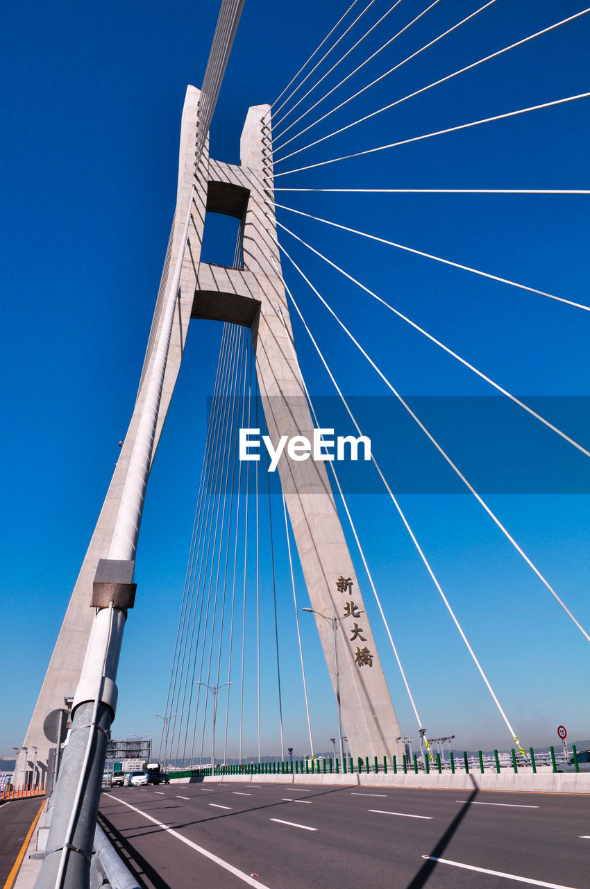 Low angle view of suspension bridge against blue sky