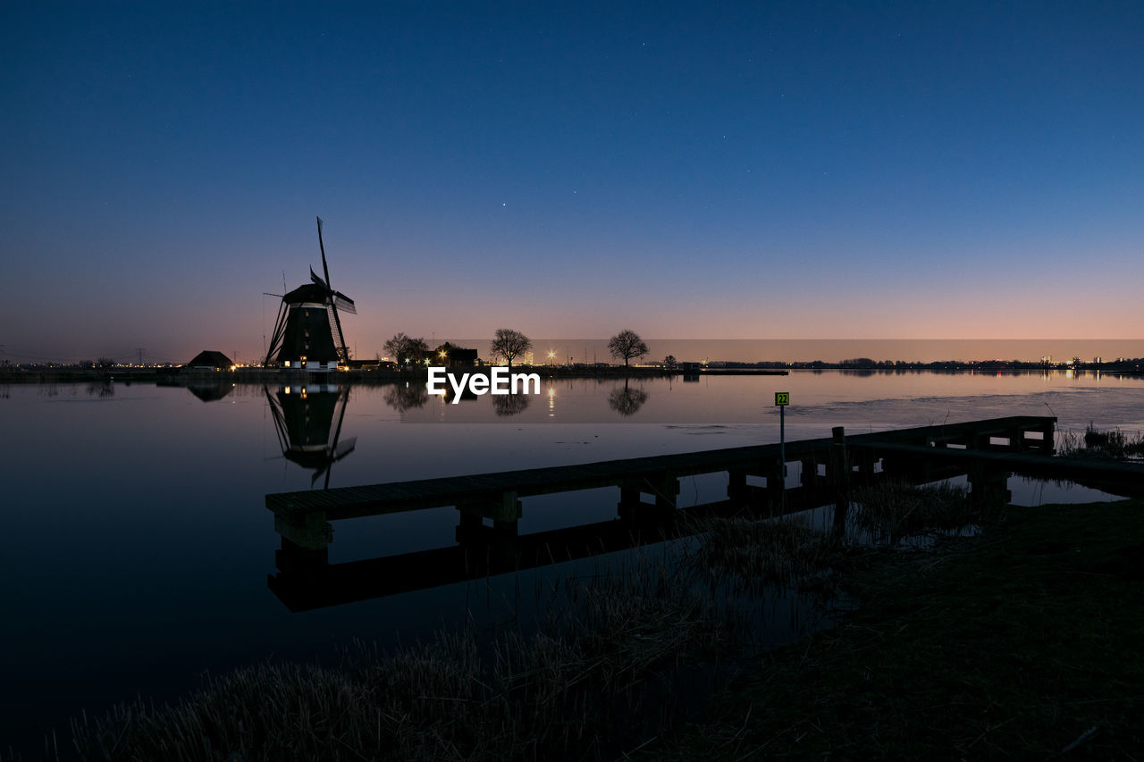 Windmill and pier along river rotte in holland during blue hour