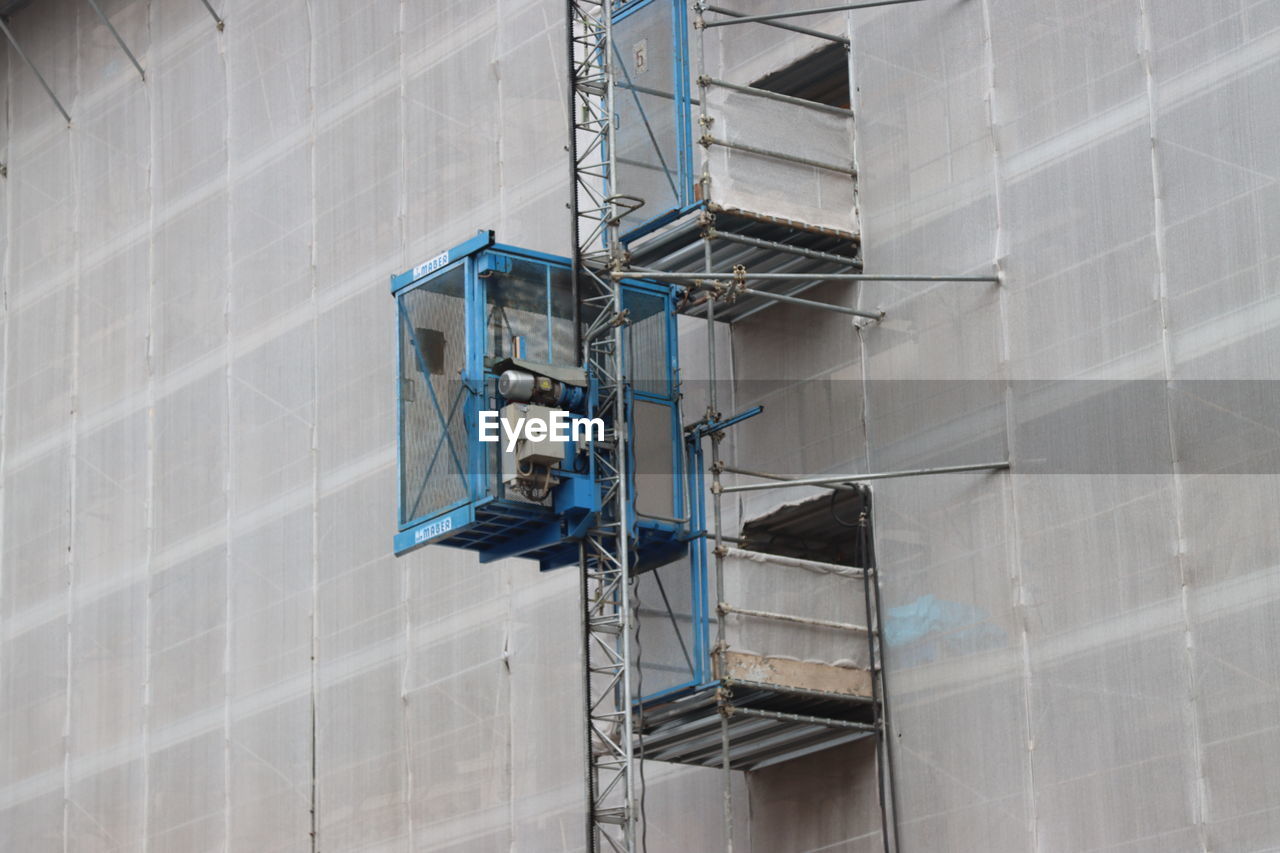 architecture, built structure, wall, building exterior, facade, building, blue, occupation, scaffolding, industry, low angle view, wall - building feature, working, construction industry, staircase, day, no people, outdoors, protection, ladder, steps and staircases, city