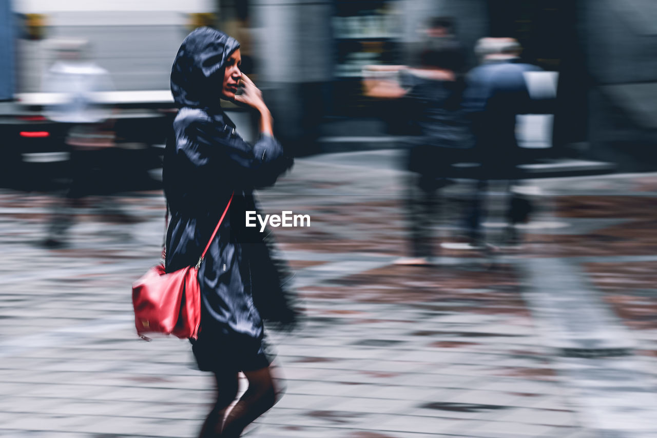 Blurred motion of woman walking on city street during rainy season
