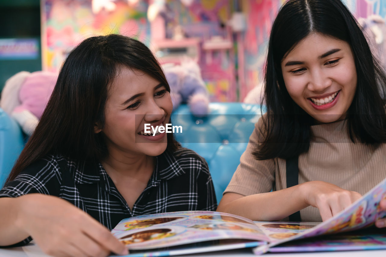 Smiling young woman with friend reading menu