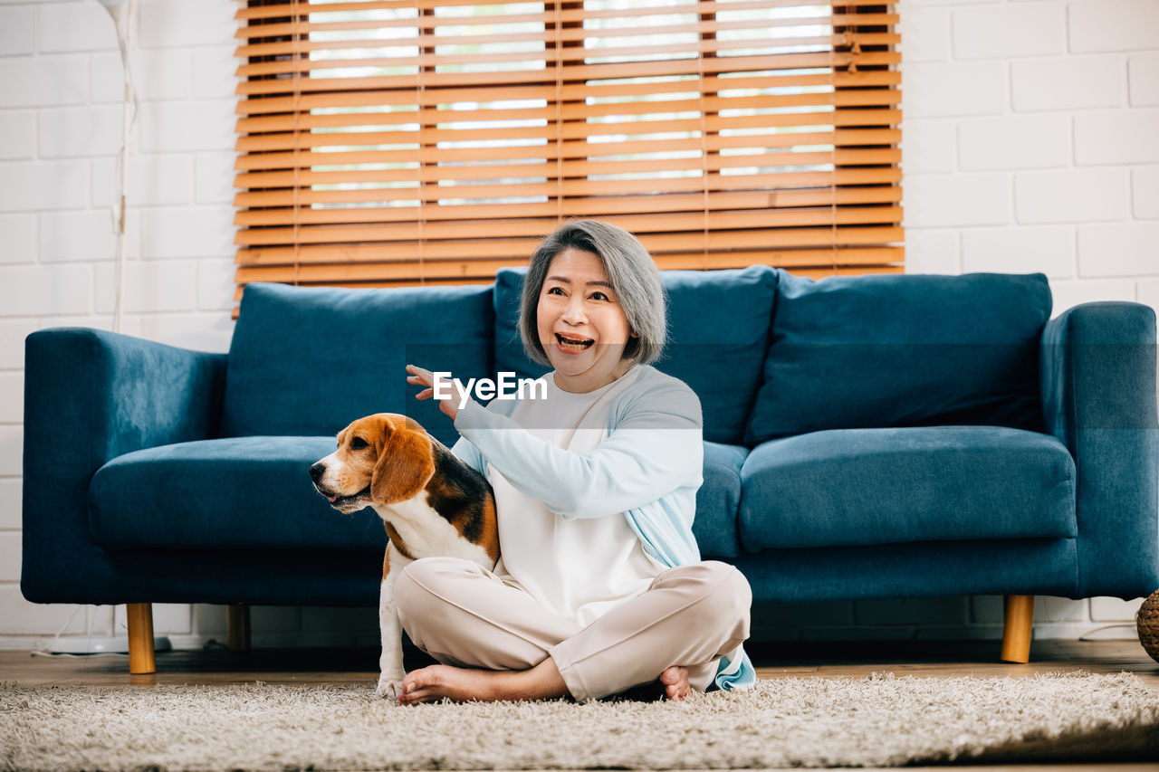 portrait of woman with dog sitting on sofa