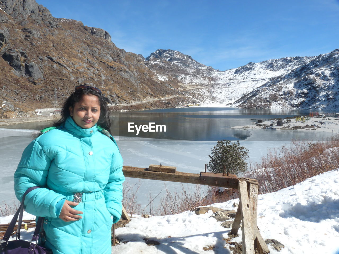 Portrait of woman standing on snowcapped mountains during winter