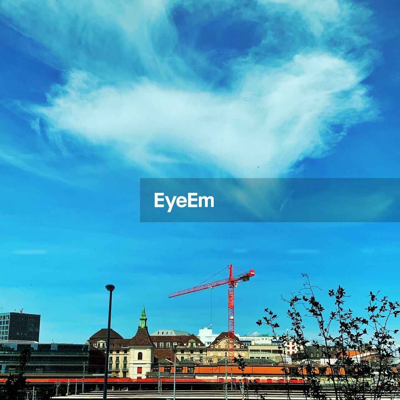 LOW ANGLE VIEW OF CRANE AND BUILDINGS IN CITY AGAINST SKY