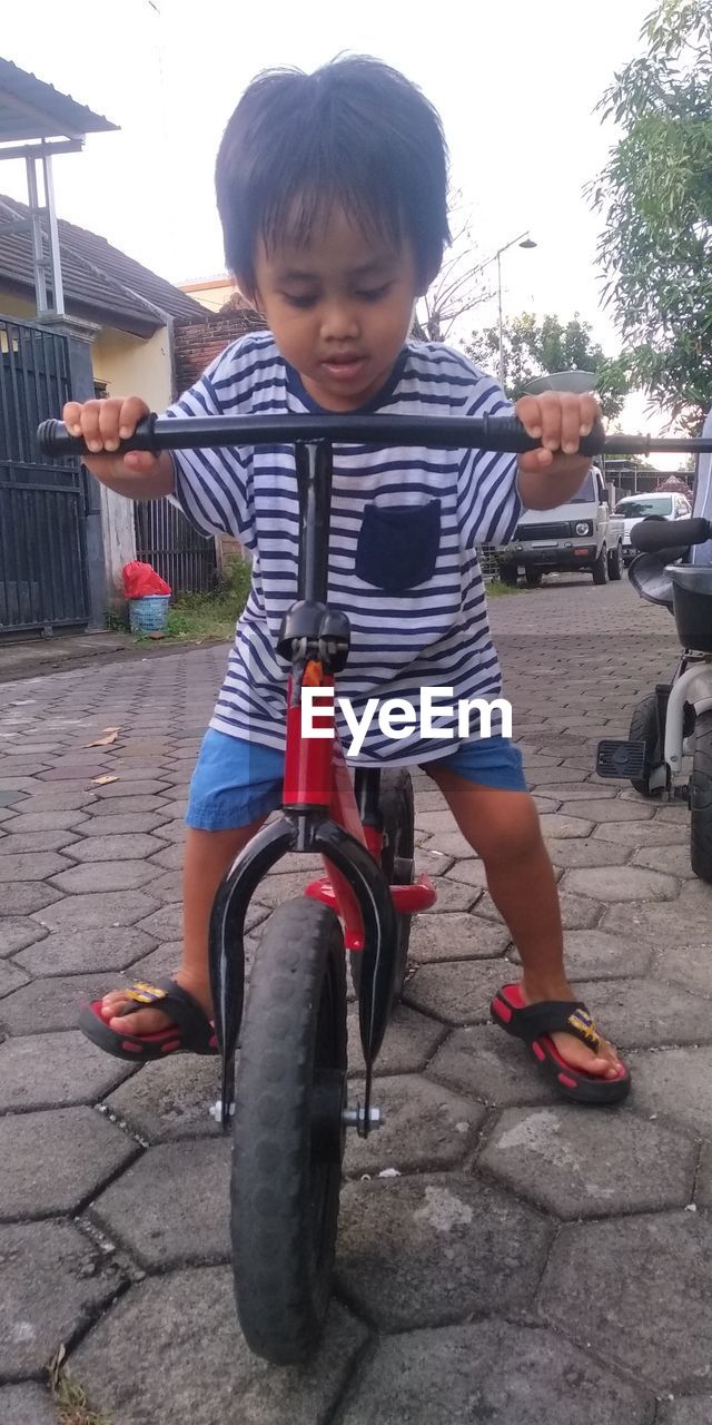 FULL LENGTH OF BOY RIDING BICYCLE ON STREET
