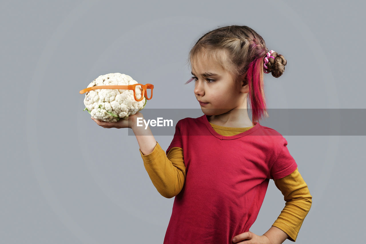 GIRL HOLDING ICE CREAM AGAINST WHITE BACKGROUND