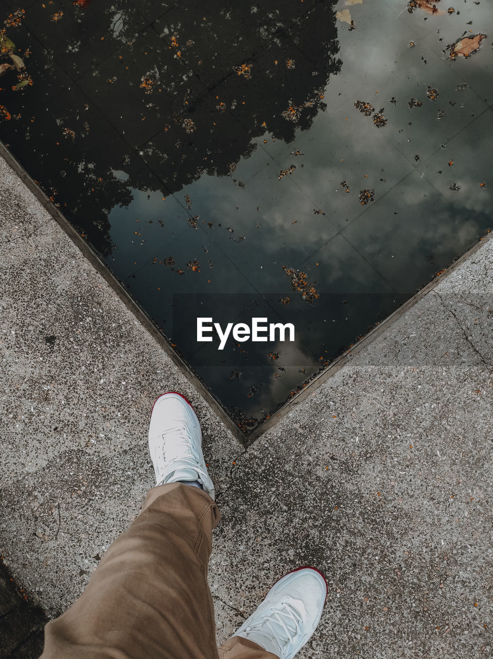 low section, human leg, shoe, high angle view, personal perspective, one person, standing, lifestyles, day, water, wall, men, directly above, leisure activity, city, human limb, limb, nature, street, human foot, footpath, outdoors, puddle, floor, reflection, road surface, black, casual clothing, asphalt, footwear, wet, road, adult, clothing, blue, white