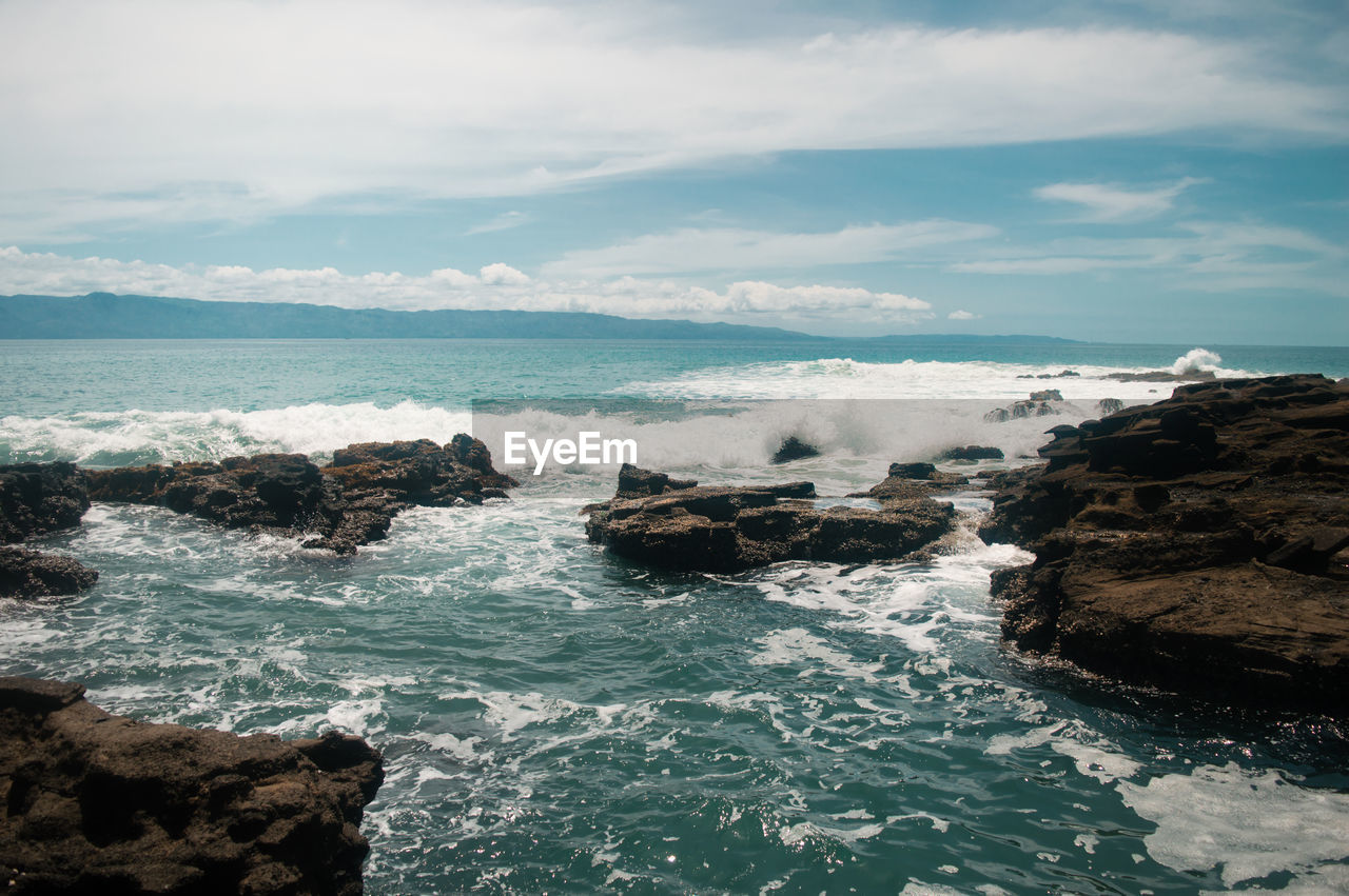 sea, water, rock, beauty in nature, solid, motion, rock - object, sky, scenics - nature, wave, sport, cloud - sky, nature, day, no people, land, aquatic sport, rock formation, beach, horizon over water, outdoors, power in nature, breaking, marine